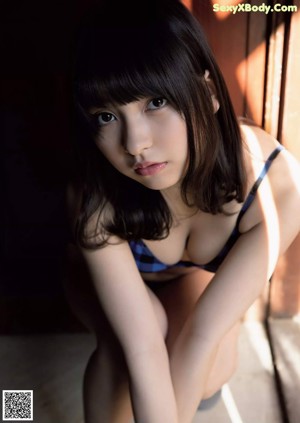A woman in a plaid shirt and blue panties posing for a picture.