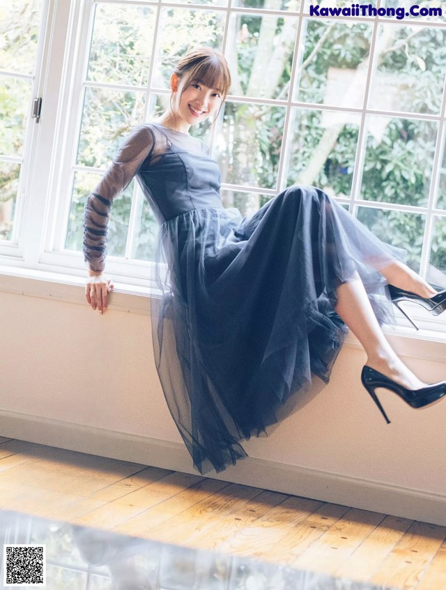 A woman in a black dress sitting on a window sill.