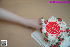 A woman sitting on a couch with a cake in front of her.