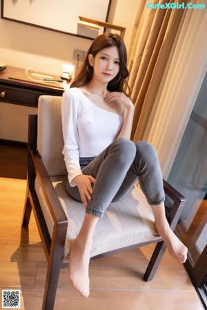 A woman in a white bodysuit sitting on a ledge.