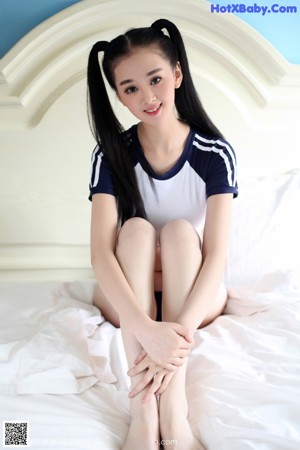 A woman in a bikini sitting on a bed.