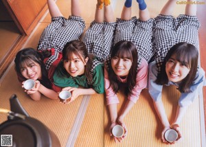 A group of young women laying on the floor with cups of coffee.