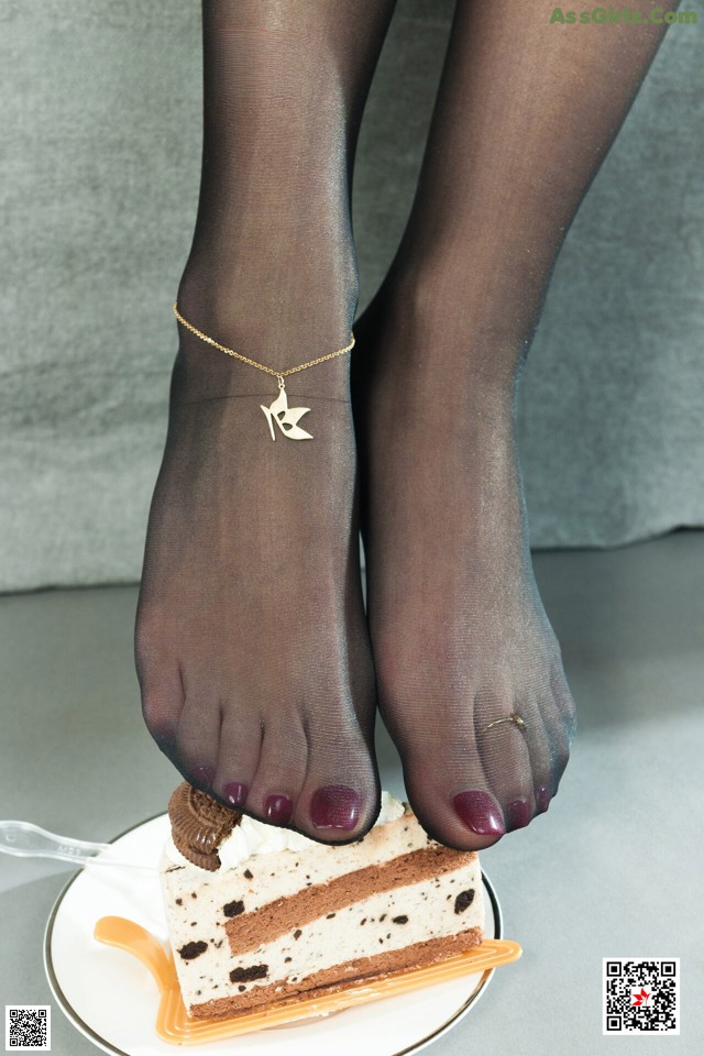 A woman's feet with a piece of cake on a plate.