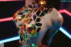 A woman in a bikini and high heels standing in front of neon lights.