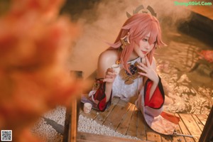 A woman with pink hair sitting on a wooden bench.