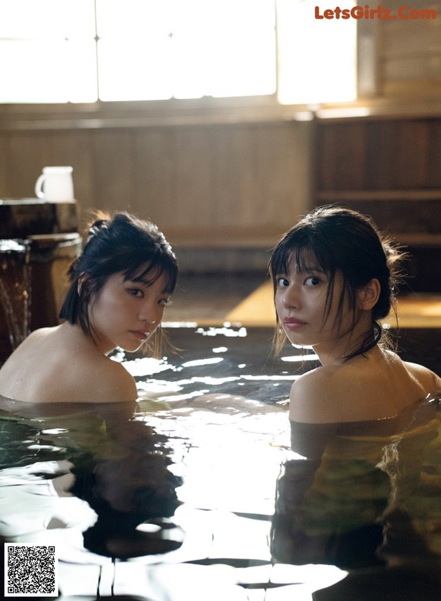 Two young women in a hot tub in a room.