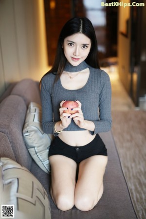 A woman sitting on a red couch talking on a cell phone.