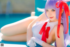 A woman in a white bathing suit standing next to a pool.