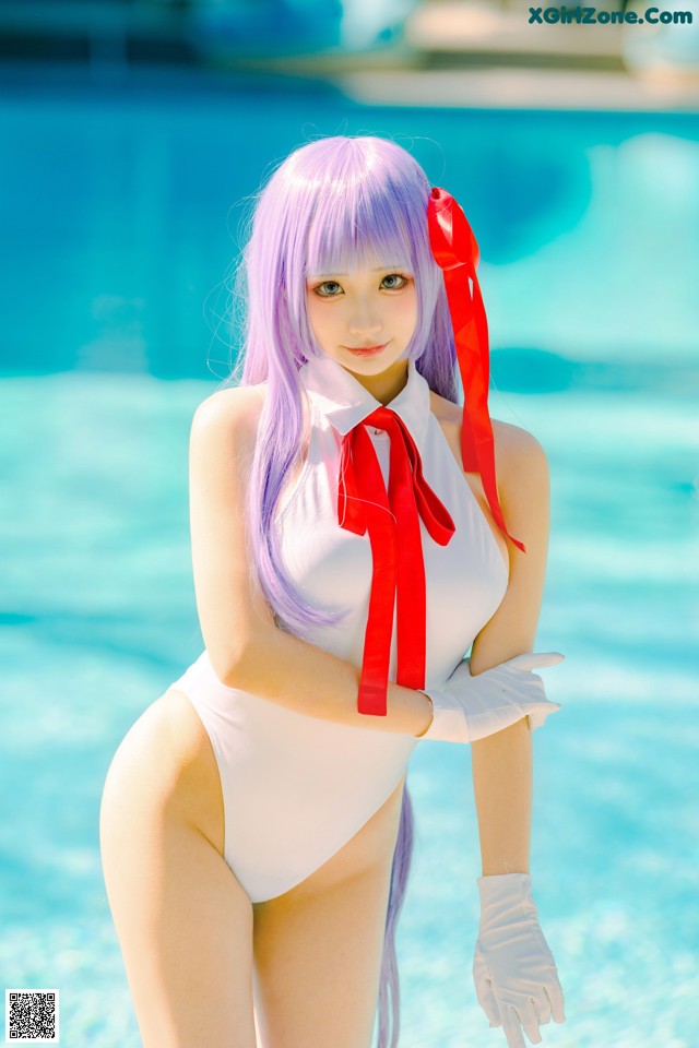 A woman in a white bathing suit standing next to a pool.