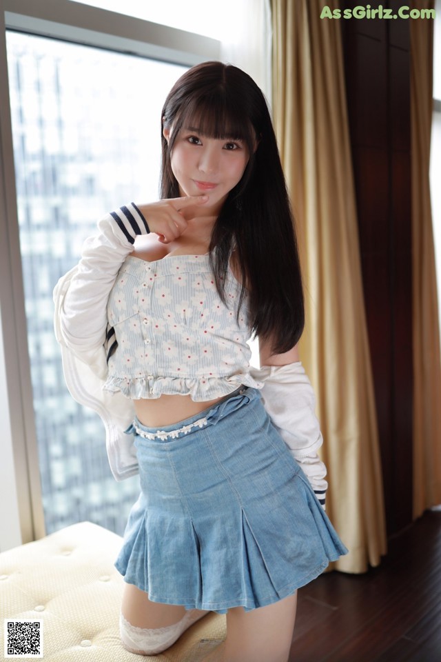 A woman in a white shirt and blue skirt posing for a picture.