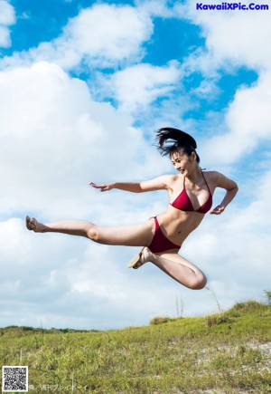 A woman in a red bikini pointing at the camera.