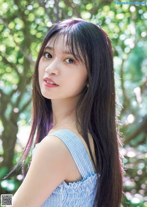 A young woman leaning against a hammock in the woods.