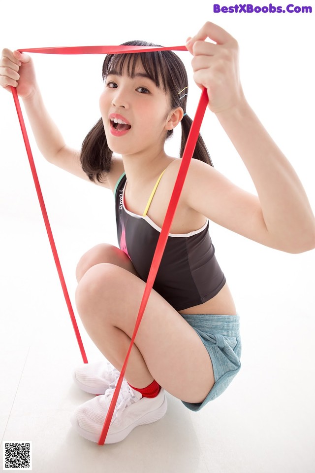 A young woman holding a red resistance band in her hands.