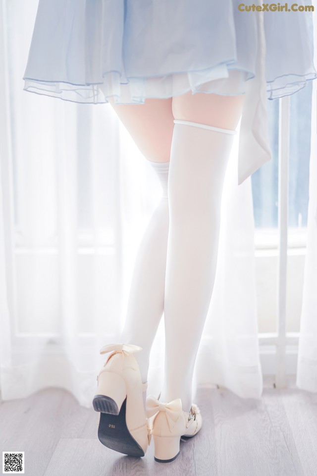 A woman wearing white stockings and a blue dress.