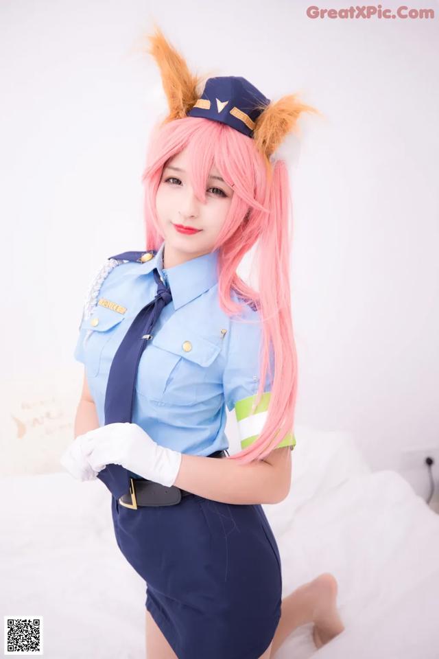 A woman in a police uniform posing on a bed.