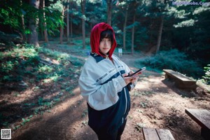 A woman dressed as a red riding hood in the woods.