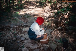 A woman in a red hooded outfit posing in the woods.