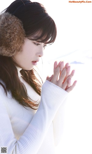 A woman with long brown hair wearing a fur ear muffs.