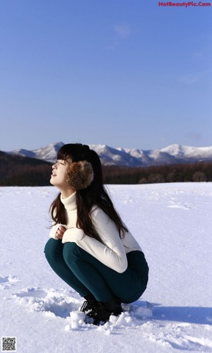 A woman crouching down in the snow with her hands on the ground.