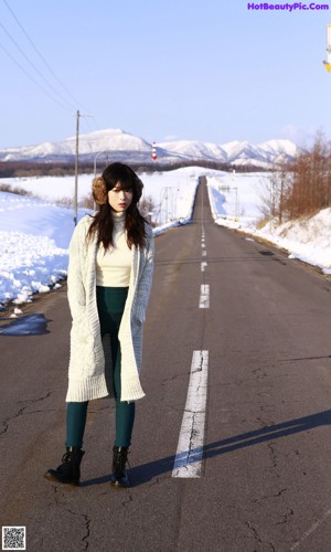 A woman wearing a white sweater and a pair of ear muffs.