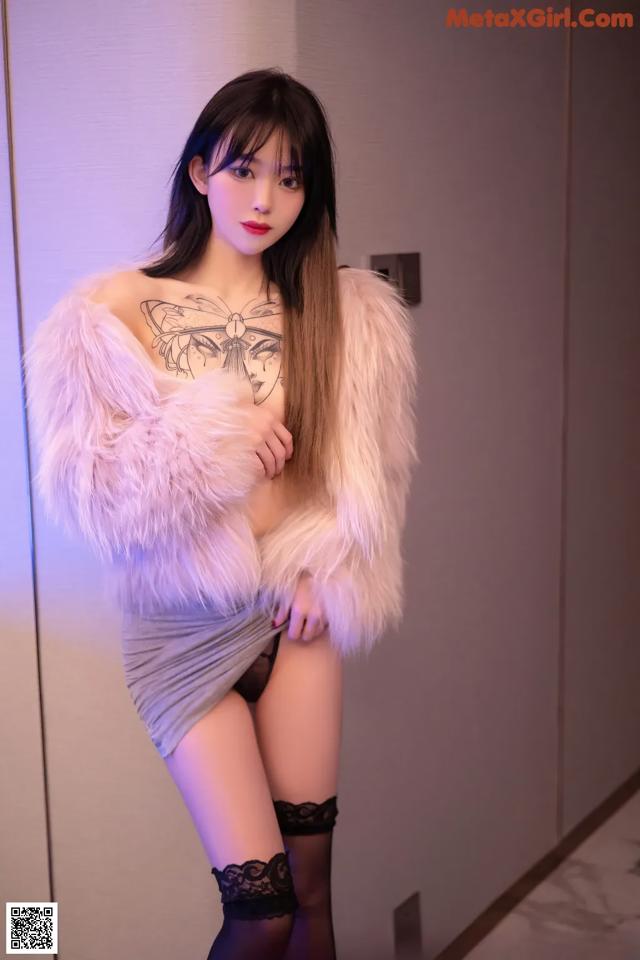 A woman in a white fur coat posing for a picture.