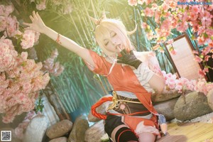 A woman in a kimono sitting on a rock next to flowers.