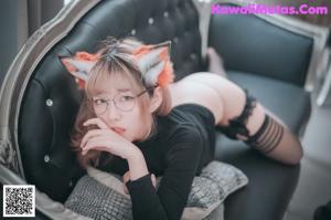 A woman in a cat ears outfit is laying on a bed.