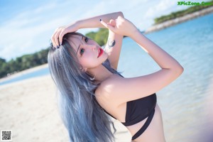 A woman in a white shirt and black shorts leaning against a palm tree.