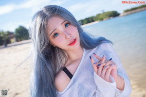 A woman with long blue hair standing on a beach.