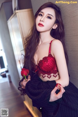 A woman in a red lingerie holding a rose.