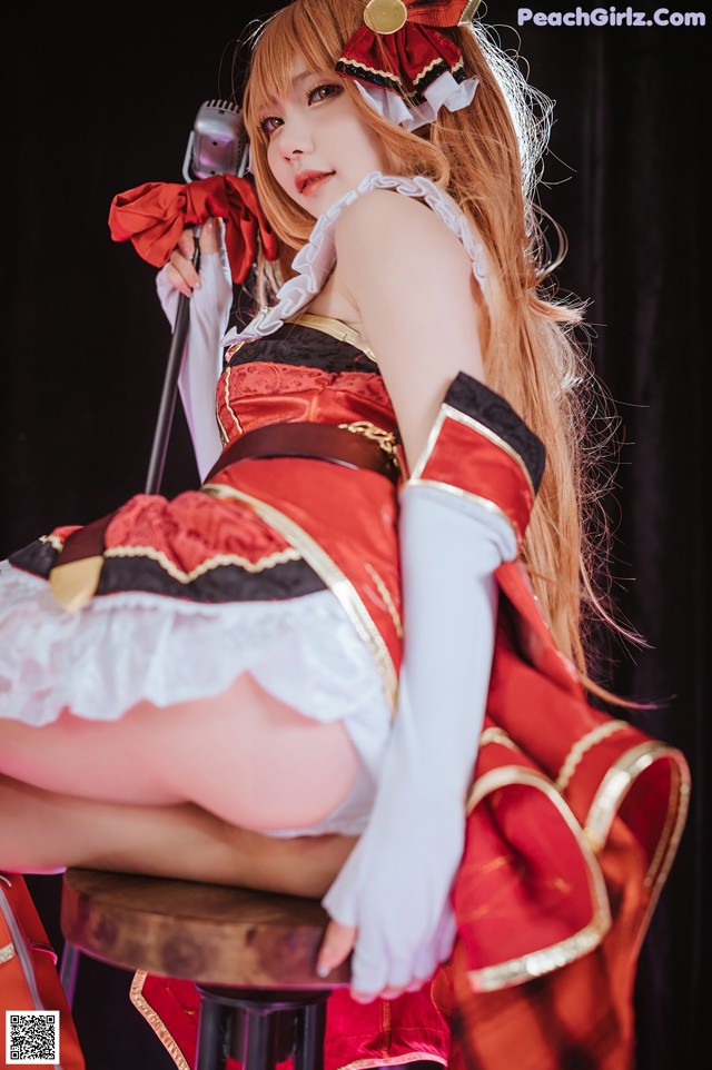 A woman in a red and white dress sitting on a stool.