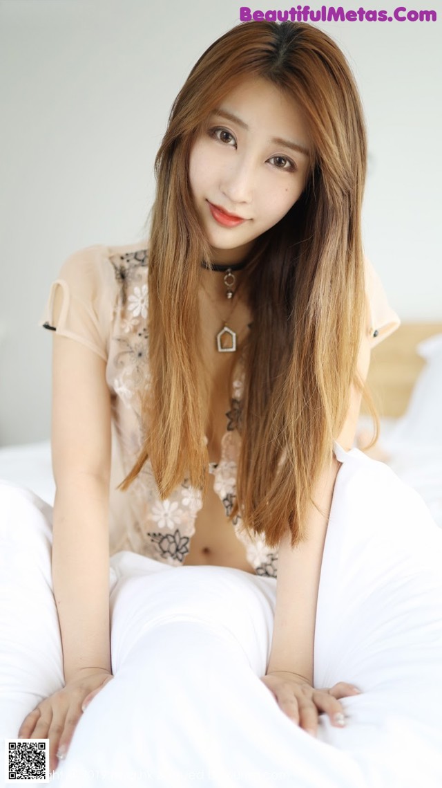 A woman sitting on top of a bed next to a pillow.