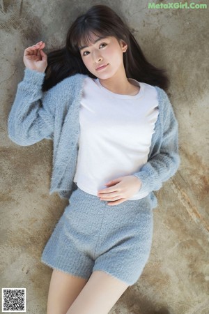 A woman in a blue sweater and skirt posing for a picture.