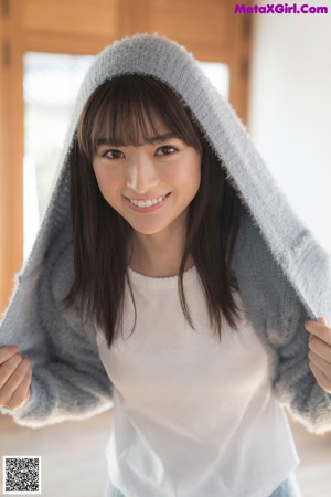 A woman in a blue sweater leaning on a wooden table.