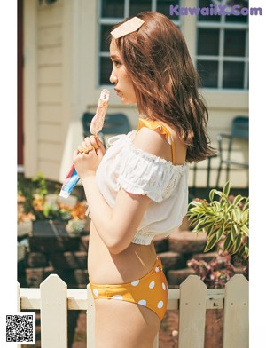 A woman in a pink bathing suit holding a colorful bag.