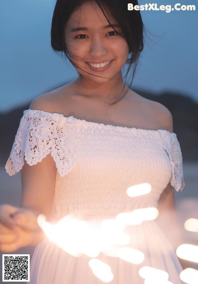 A woman in a white dress holding a string of lights.