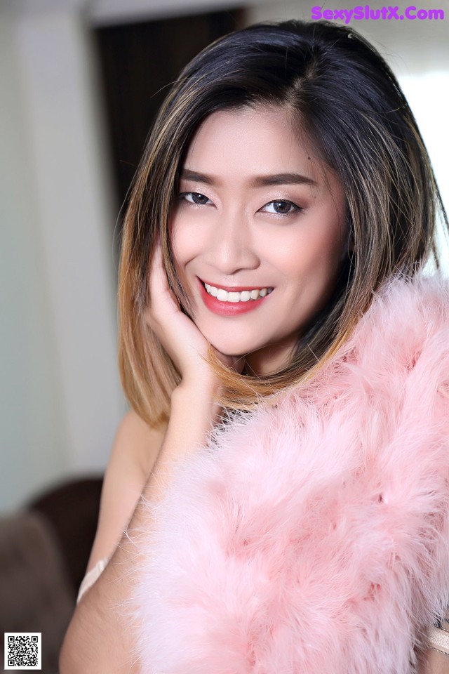 A woman in a pink fur coat posing for a picture.