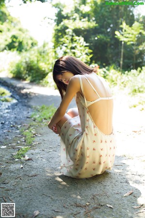 A young girl laying on a rock looking at the camera.