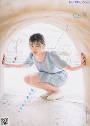 A woman in a striped dress crouching down in a tunnel.