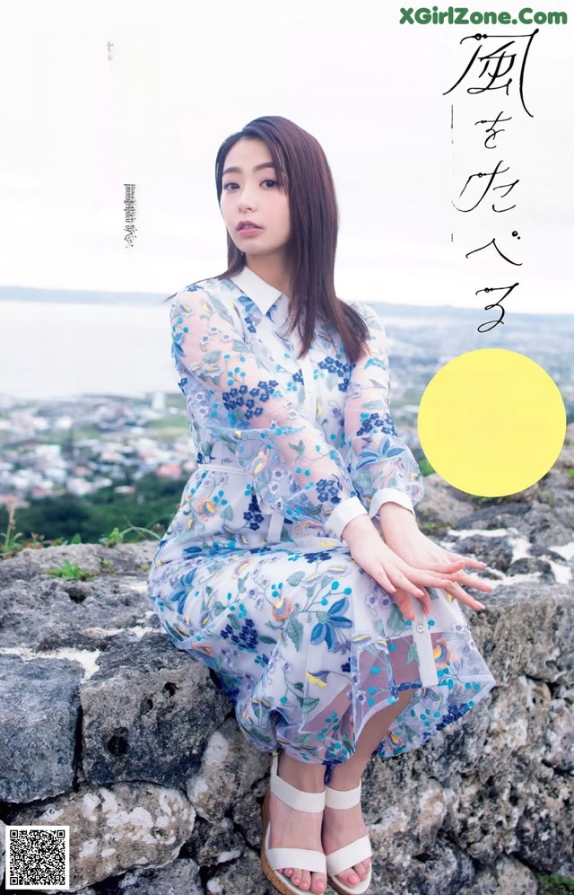 A woman sitting on top of a stone wall.