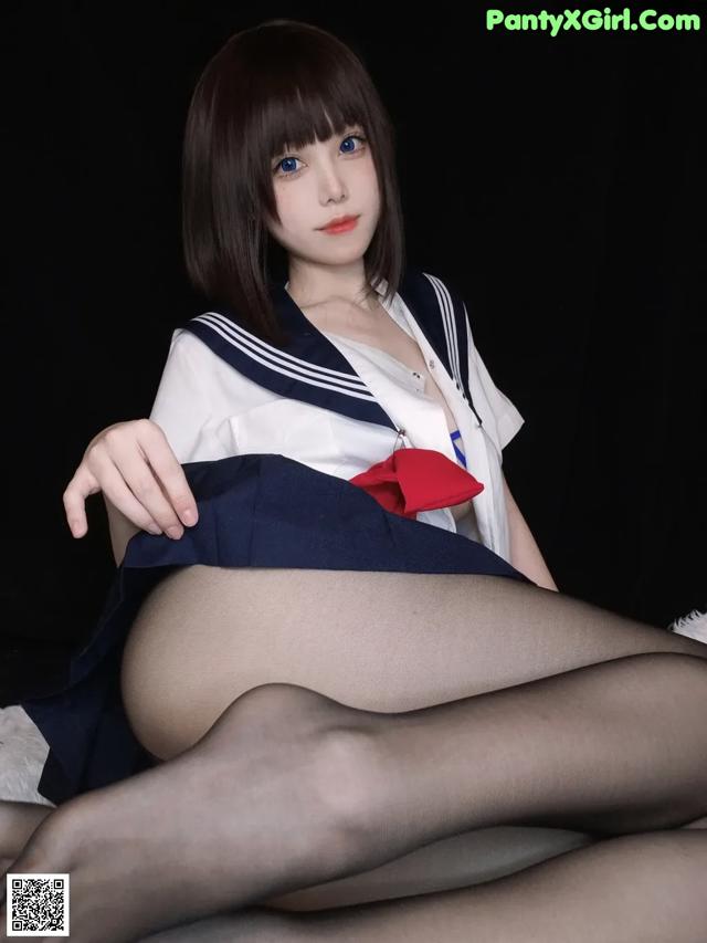 A woman in a sailor outfit is sitting on a bed.