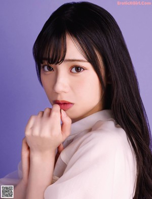 A woman with long black hair wearing a white blouse.