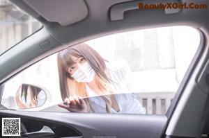 A woman wearing a face mask sitting in a car.