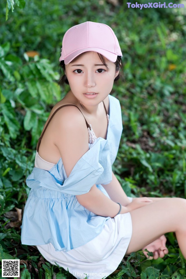 A woman in a pink hat sitting on the ground.