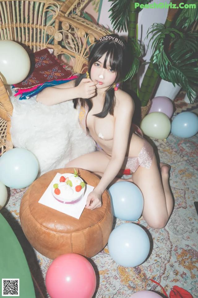 A woman sitting on the floor with a birthday cake.