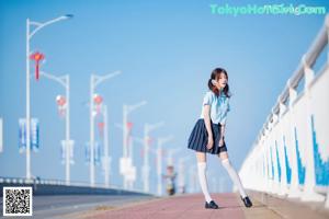 A woman in a blue shirt and skirt posing for a picture.