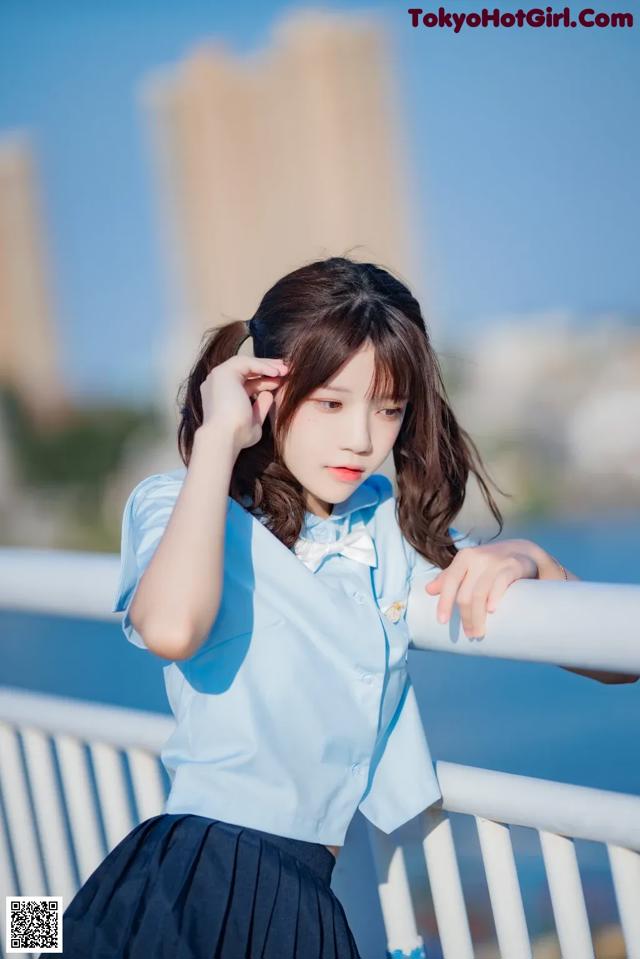 A woman in a blue shirt and black skirt posing for a picture.