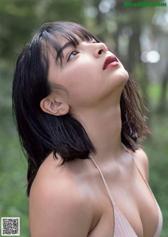 A woman in a pink bikini posing in the woods.