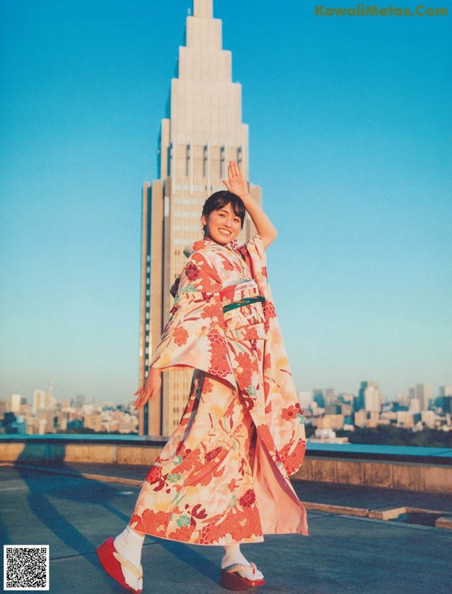 A woman in a kimono standing in front of a tall building.
