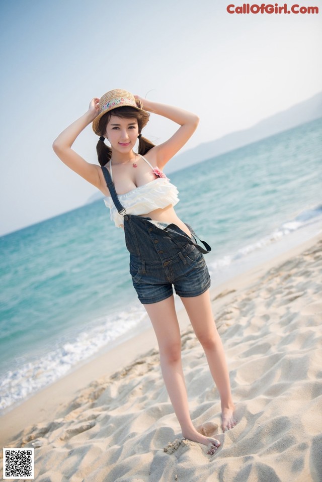 A woman standing on a sandy beach next to the ocean.